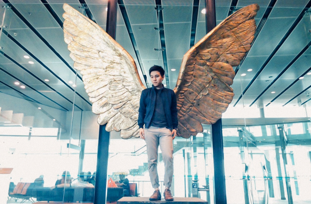 Picture of a young man posing in front of a sculpture of wings at Changi Airport Terminal 3